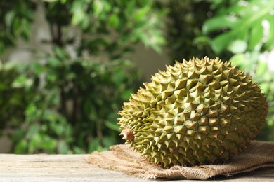Photo of Ripe durian on wooden table against blurred background. Space for text
