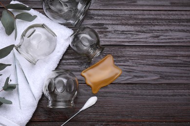 Cupping set, gua sha and eucalyptus on wooden table, flat lay. Space for text