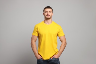 Photo of Man wearing yellow t-shirt on light grey background. Mockup for design