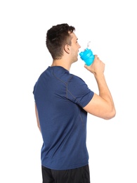 Young man drinking protein shake on white background