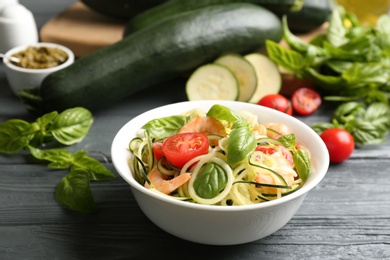 Photo of Delicious zucchini pasta with shrimps, cherry tomatoes and basil on grey wooden table