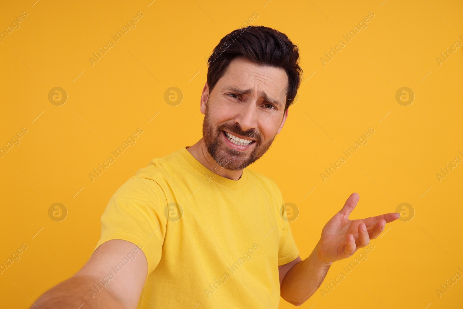 Photo of Emotional man taking selfie on yellow background