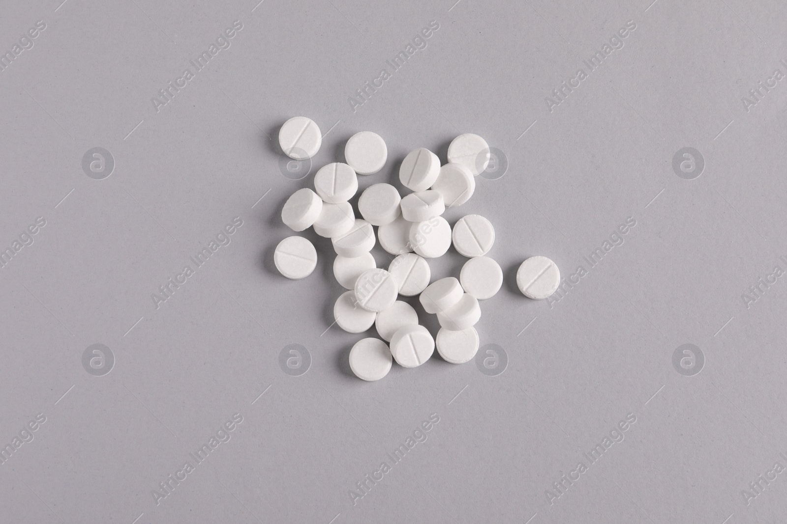 Photo of Pile of round pills on light grey background, top view