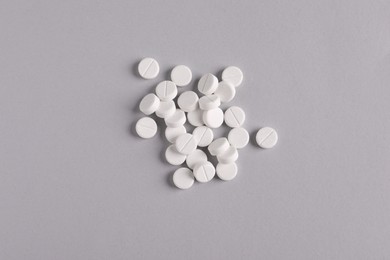 Photo of Pile of round pills on light grey background, top view