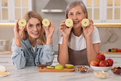 Happy mature mother and her daughter having fun in kitchen