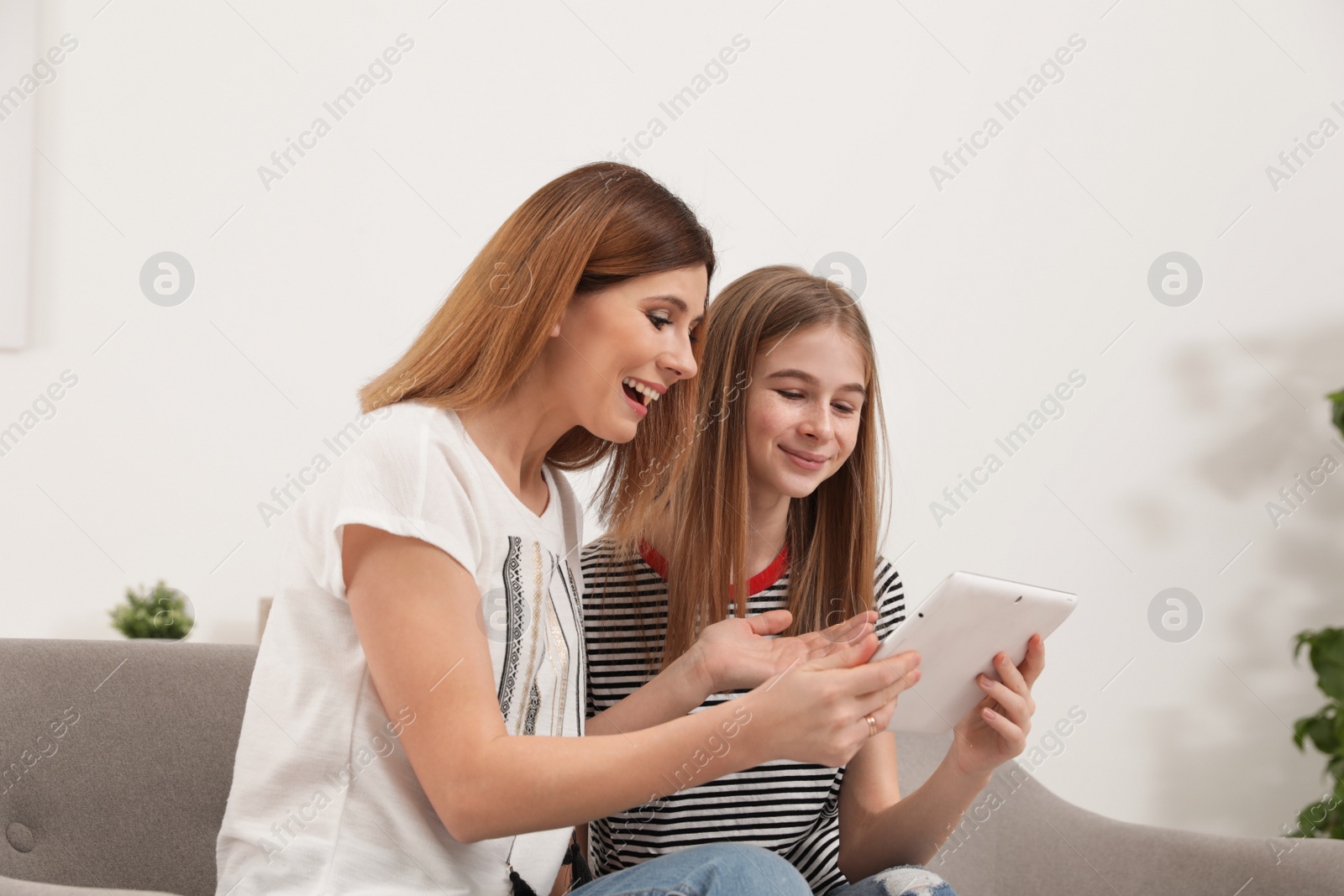 Photo of Happy mother and her teenager daughter with tablet computer at home
