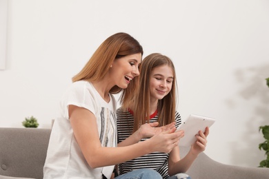 Happy mother and her teenager daughter with tablet computer at home