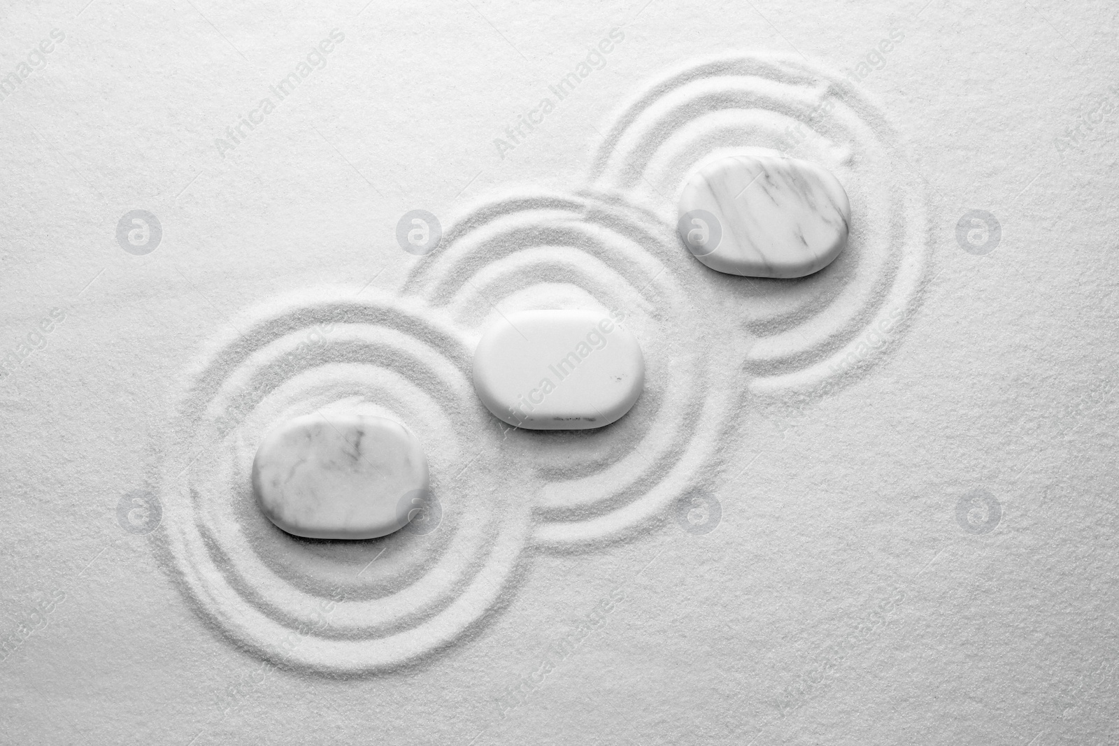 Photo of White stones on sand with pattern, flat lay. Zen, meditation, harmony