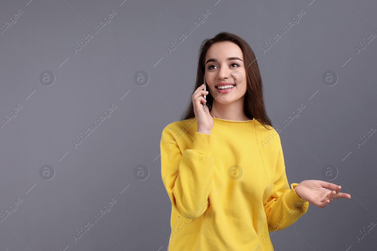 Photo of Young woman talking on phone against color background