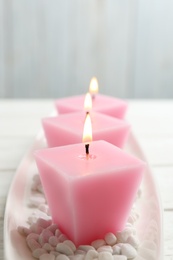 Composition with three burning candles on white table