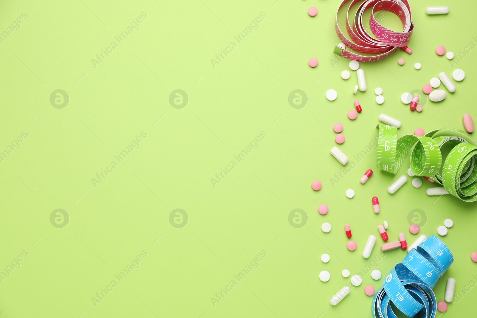 Photo of Weight loss pills and measuring tapes on green background, flat lay. Space for text