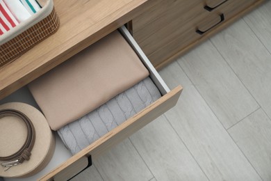 Photo of Chest of drawers with different folded clothes and accessories indoors, top view. Space for text