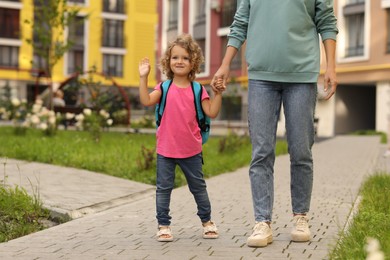 Photo of Woman and her little daughter on their way to kindergarten outdoors, closeup. Space for text