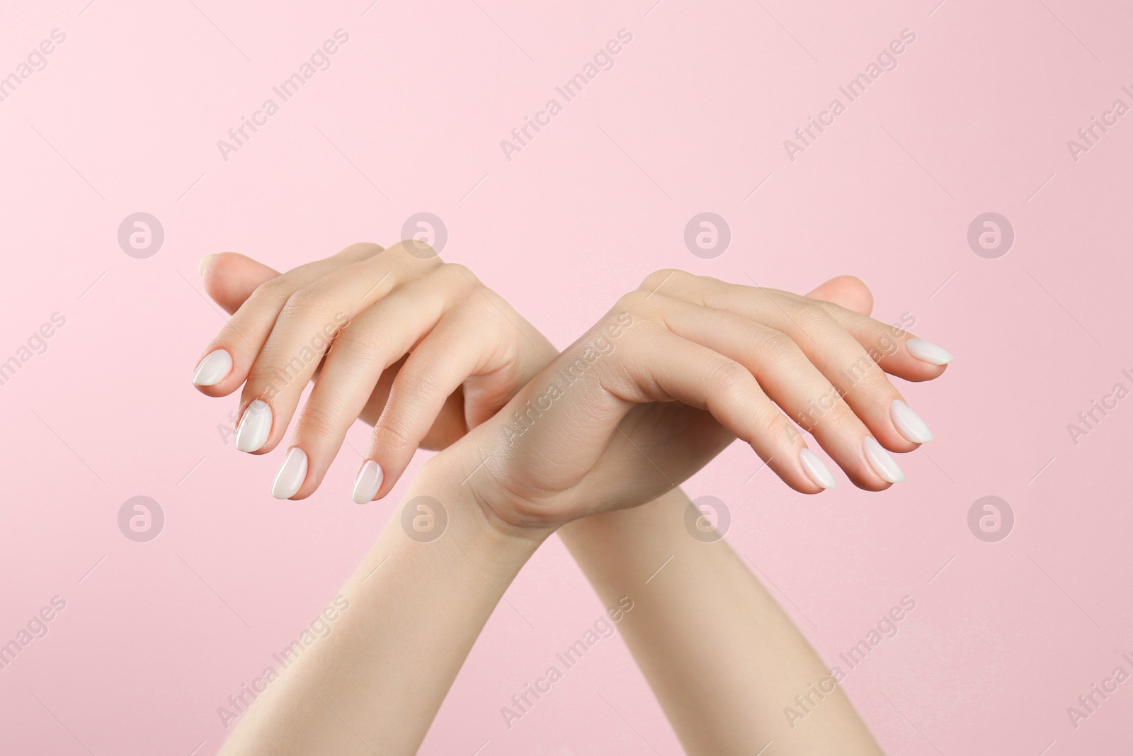 Photo of Woman with white polish on nails against pink background, closeup