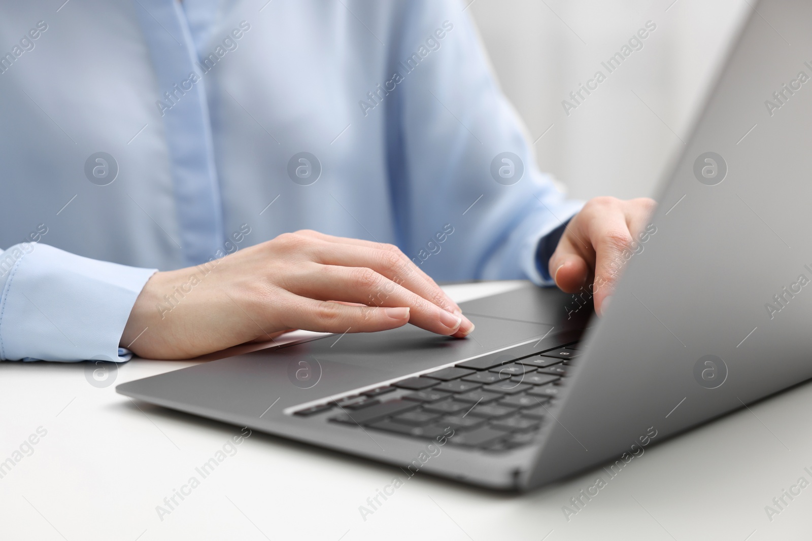 Photo of E-learning. Woman using laptop at white table indoors, closeup
