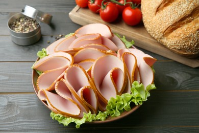 Photo of Slices of delicious boiled sausage and other products on dark wooden table