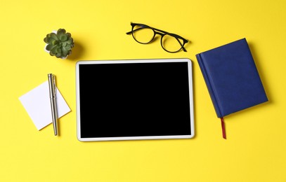 Photo of Online store. Tablet, stationery, glasses and houseplant on yellow background, flat lay
