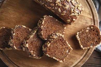 Photo of Tasty rye bread on wooden board, top view