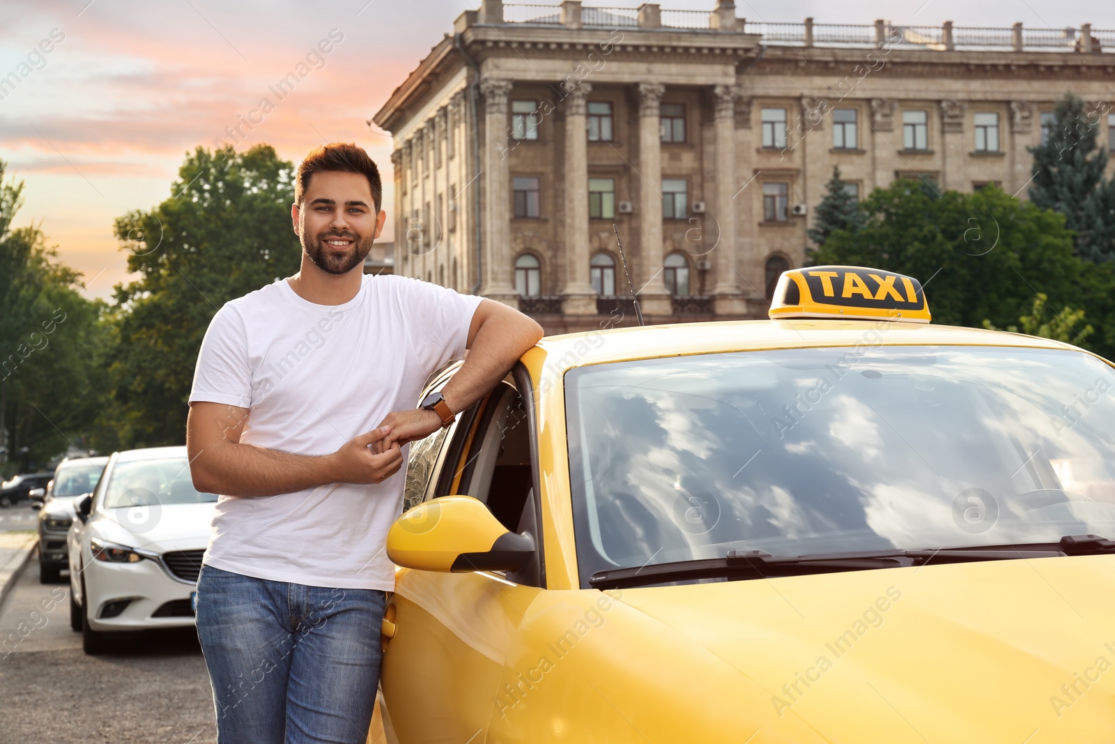 Photo of Handsome taxi driver near car on city street