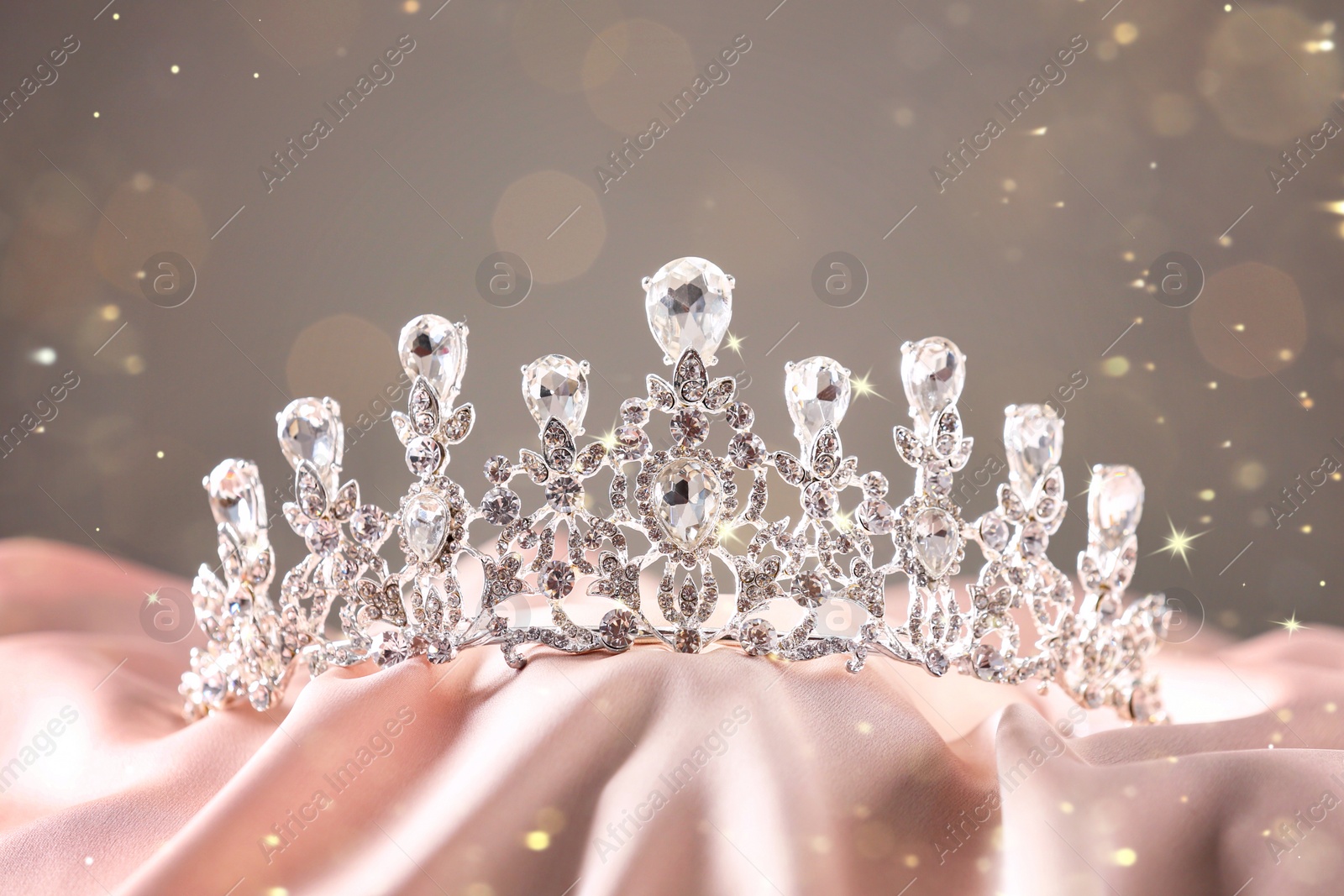 Image of Beautiful silver tiara with diamonds on pink cloth, bokeh effect