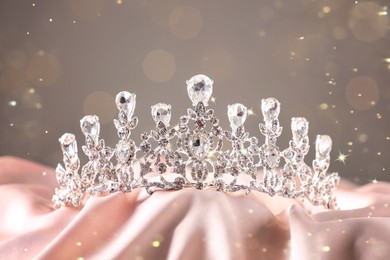 Image of Beautiful silver tiara with diamonds on pink cloth, bokeh effect