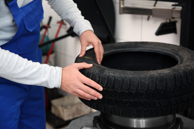 Photo of Mechanic working with tire fitting machine at car service, closeup