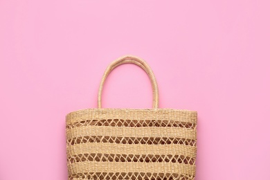 Elegant woman's straw bag on pink background, top view