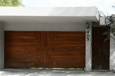 Photo of Beautiful new automated wooden gates and white wall outdoors
