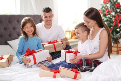 Happy parents and children exchanging gifts on Christmas morning at home