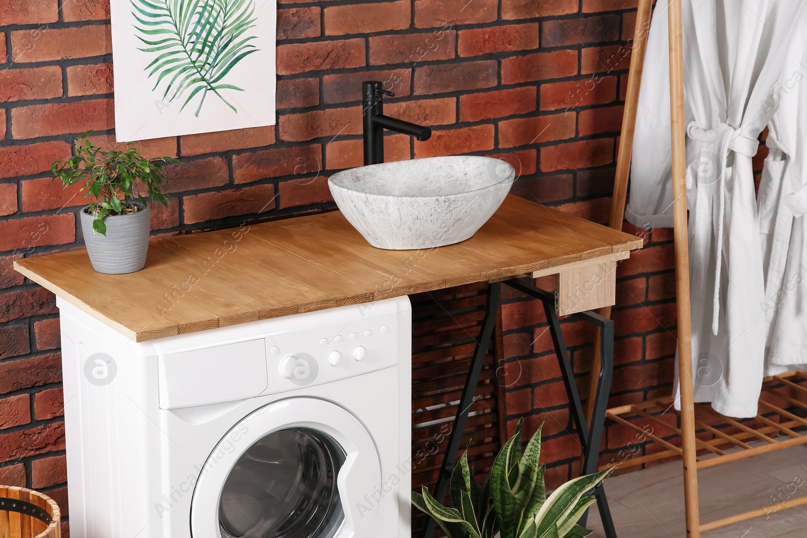 Photo of Washing machine, sink and potted plants indoors. Laundry room interior design