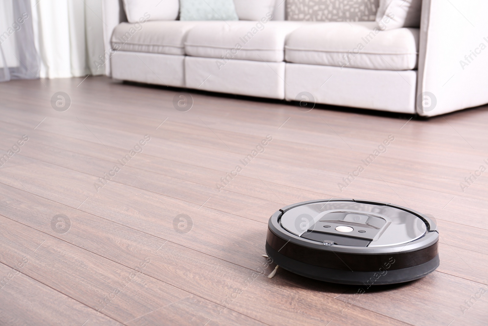 Photo of Hoovering floor with modern robotic vacuum cleaner indoors. Space for text