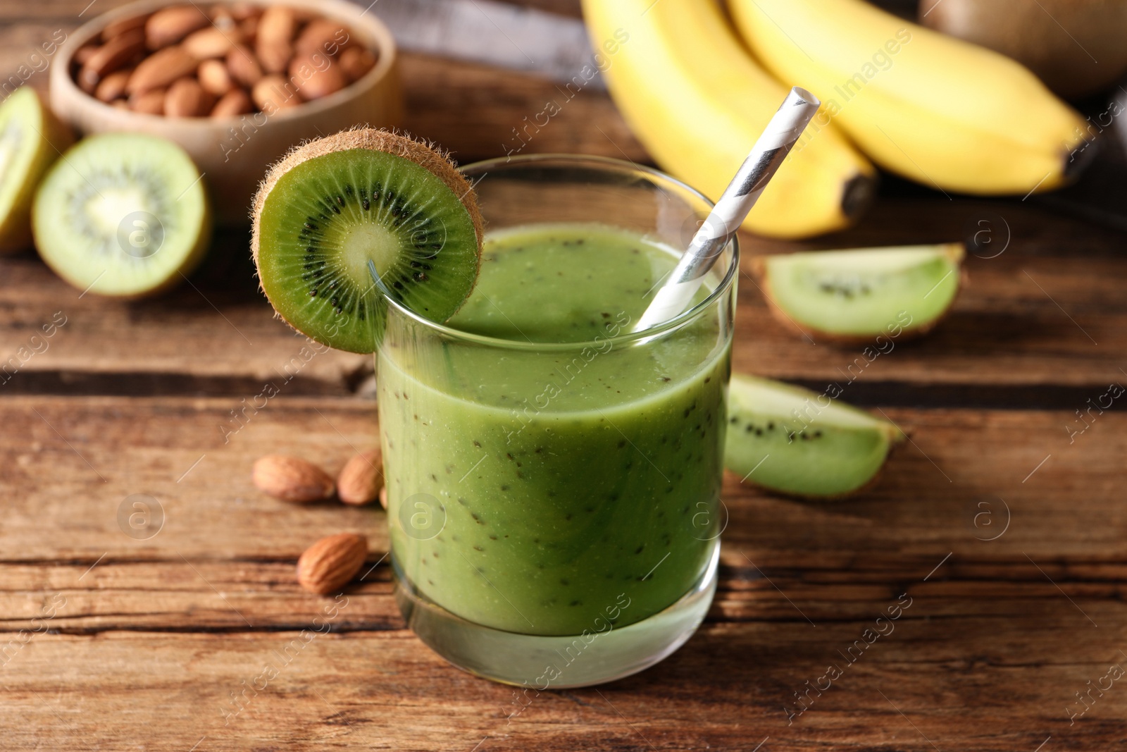 Photo of Delicious kiwi smoothie and ingredients on wooden table