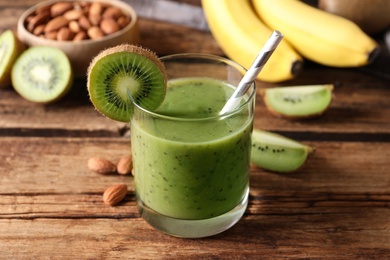 Photo of Delicious kiwi smoothie and ingredients on wooden table