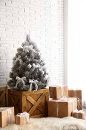 Photo of Stylish room interior with beautiful Christmas tree and gifts near white brick wall