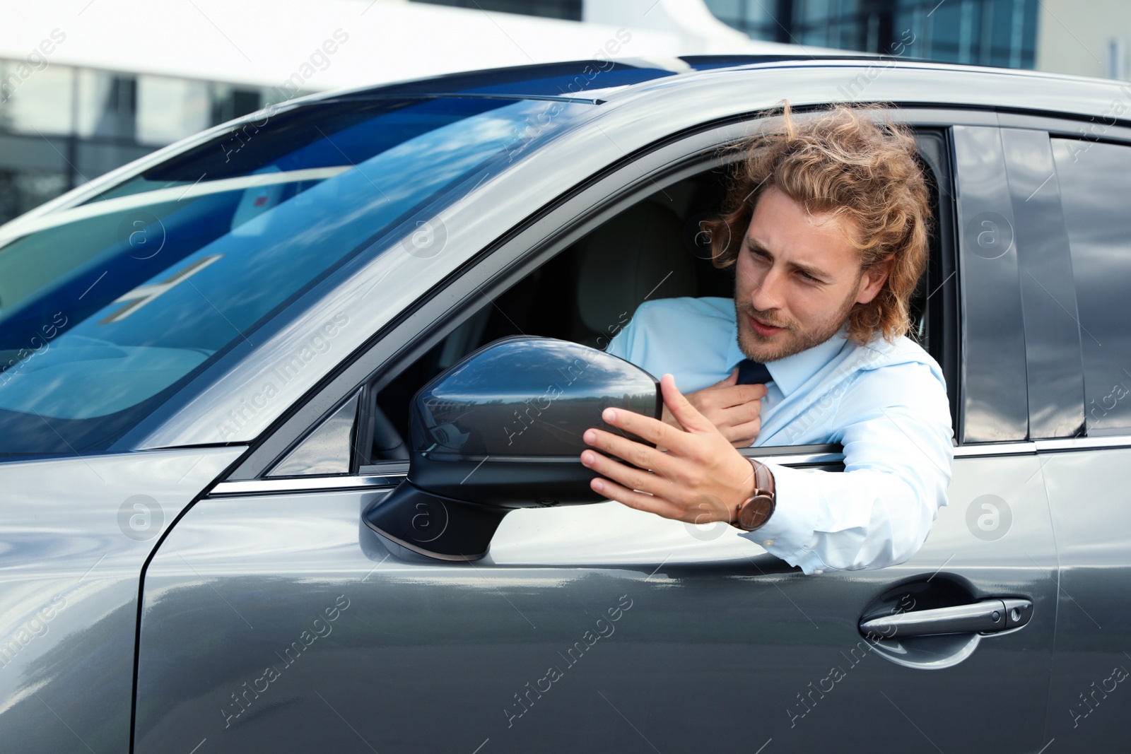 Photo of Attractive young man straightens tie in his luxury car