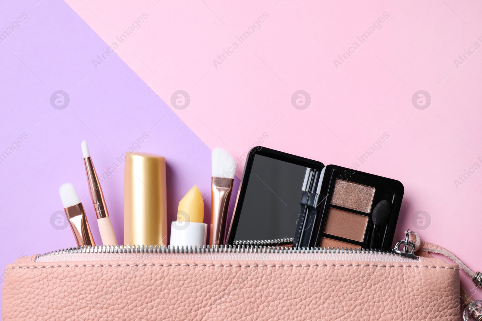 Photo of Bag with hygienic lipsticks and cosmetic products on color background, flat lay. Space for text