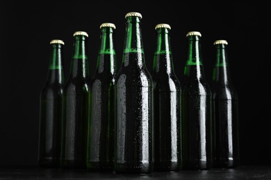 Glass bottles of beer on table against black background