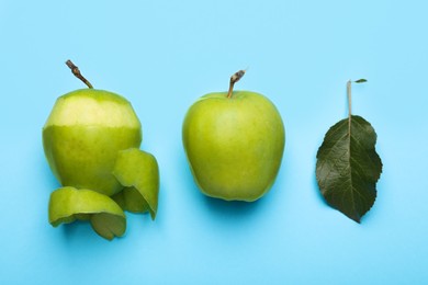 Photo of Ripe green apples with peels and leaf on light blue background, flat lay