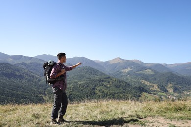 Photo of Tourist with backpack enjoying view in mountains on sunny day