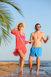 Happy young couple walking together on beach