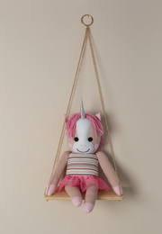 Photo of Shelf with cute toy unicorn on beige wall. Child's room interior element