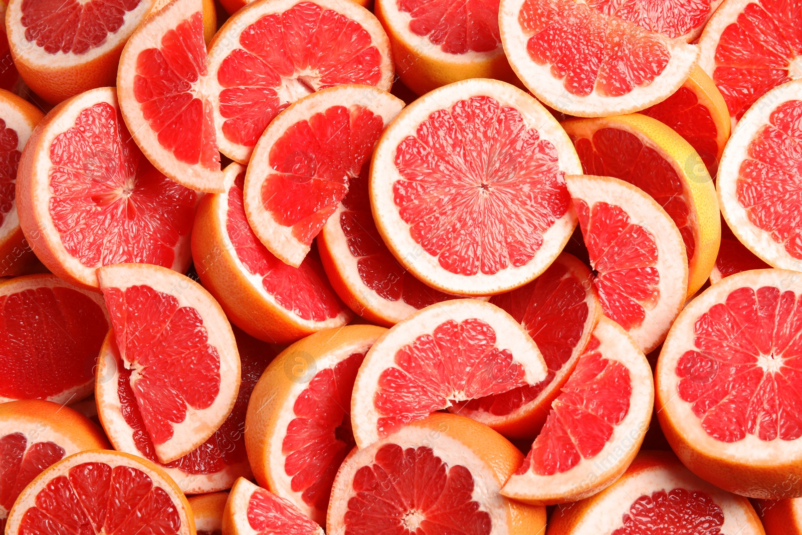 Photo of Many sliced fresh grapefruits as background, top view