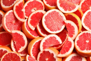 Photo of Many sliced fresh grapefruits as background, top view