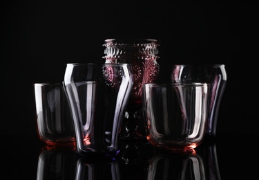 Photo of Set of different colorful empty glasses on black background