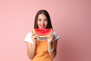 Beautiful young woman posing with watermelon on color background