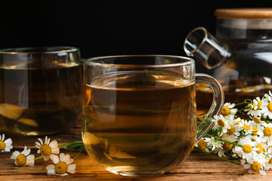 Photo of Cup of tea and chamomile flowers on wooden table