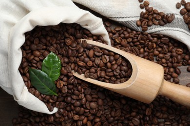 Scoop and bag with roasted coffee beans on wooden table, flat lay