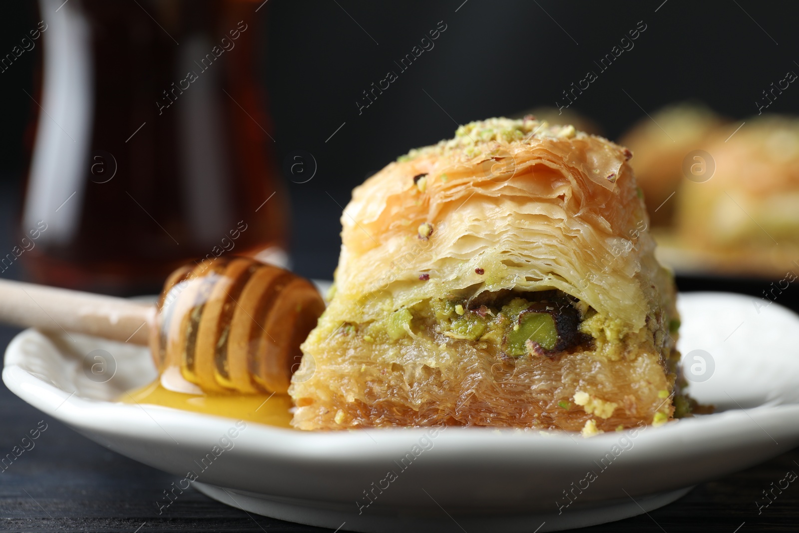 Photo of Delicious fresh baklava with chopped nuts and honey on table, closeup. Eastern sweets