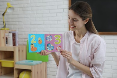 Photo of Happy female English teacher giving lesson in elementary school