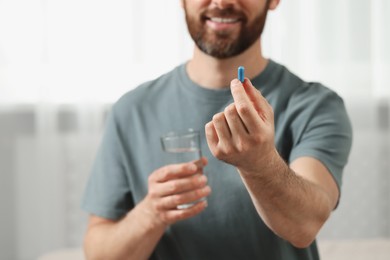 Photo of Man with glass of water and pill indoors, closeup